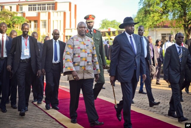 FILE - South Sudan's rebel leader and now Vice President Riek Machar, center-left, walks with President Salva Kiir, center-right, after being sworn in at the presidential palace in the capital Juba, South Sudan, April 26, 2016.