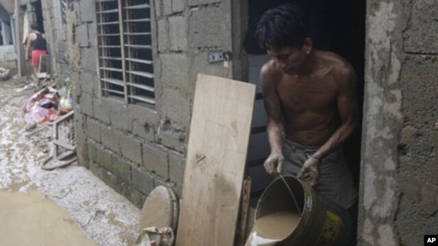 Ramon Fabros pours muddy water out of his house after floodwaters brought by Typhoon Nesat receded,  September 28, 2011 in suburban San Mateo, eastern of Manila, Philippines.