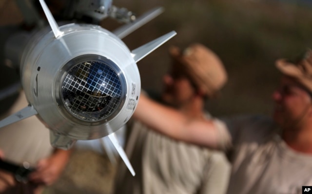 FILE In this photo taken from Russian Defense Ministry official web site on Tuesday, Oct. 6, 2015, Russian military support crew inspect missiles attached to their jet at an air base in Syria. at an air base Hmeimim in Syria.