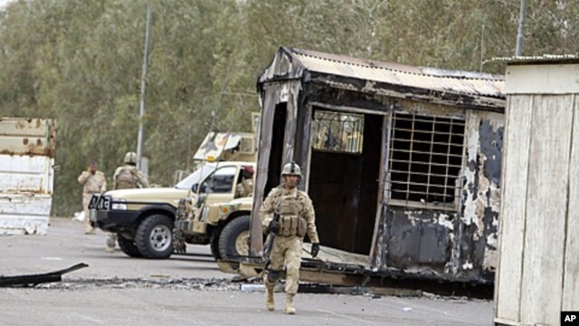 Iraqi Army soldiers stand guard near burned trailers at Camp Ashraf north of Baghdad, Iraq, April 8, 2011 (file photo).
