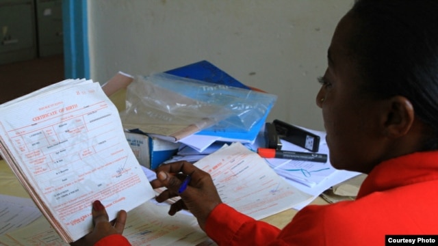 Benedetta Kamene, Volunteer Children's Officer, reviews a stack of newly-issued birth certificates at the Kimadzo community-based organization, Kwale, Kenya, July 25, 2012. (VOA/Jill Craig)