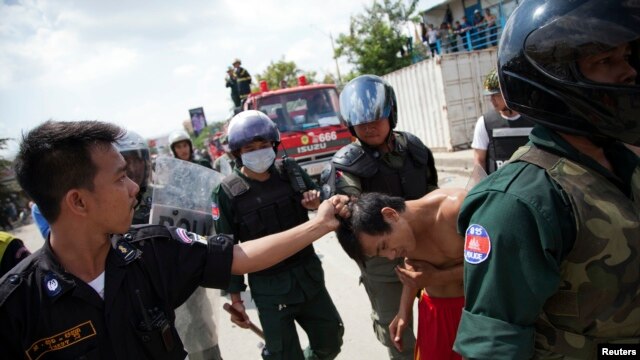 FILE - Security forces detain a man during clashes with garment workers in Phnom Penh, Cambodia, Nov. 12, 2013.