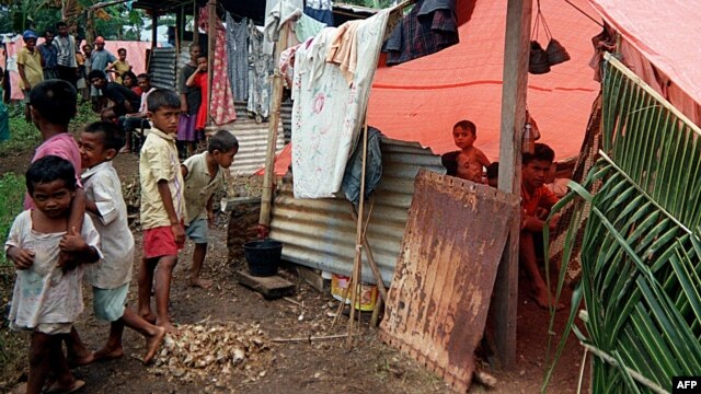 People shelter from the heat of sun in a refugee camp in Morotai, North Maluku, June 21, 2000.