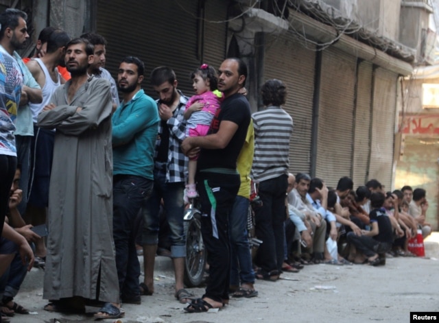 FILE - People queue for bread in the rebel held al-Shaar neighborhood of Aleppo, Syria, July 14, 2016.