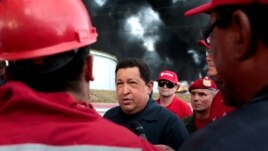 El presidente venezolano Hugo Chávez conversa con trabajadores de PDVSA mientras la refinería de Amuay arde todavía en el fondo, el domingo 26 de agosto de 2012.