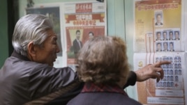 A Chinese couple look at a newspaper reporting on new General Secretary of Communist Party of China Xi Jinping and other members of the party leadership in Beijing, China,  Nov. 16, 2012. 