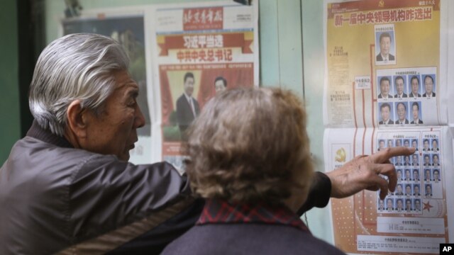 A Chinese couple look at a newspaper reporting on new General Secretary of Communist Party of China Xi Jinping and other members of the party leadership in Beijing, China,  Nov. 16, 2012. 