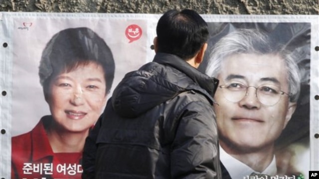 Một người dân dừng lại xem hình 2 ứng cử viên tổng thống Nam Triều Tiên Park Geun-hye (trái), và Moon Jae-in