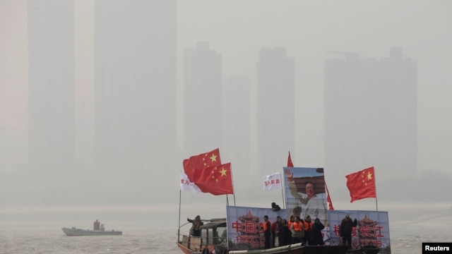 12月26日在湖北武汉，打着中国国旗、展示已故中共领导人毛泽东巨幅画像的船只引领着人们进行冬泳