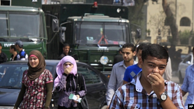 Egyptians cover their faces to avoid tear gas vapor as they walk at the site of clashes between protesters and anti-riot policemen near the Israeli Embassy in Cairo, Egypt, Sept. 10, 2011.