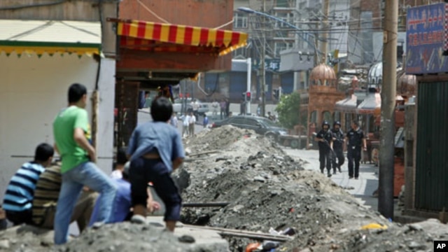 Ethnic Uighurs look on as Chinese security forces stand by the entrance to the Uighurs neighborhood in Urumqi in China's Xinjiang autonomous region, July 8, 2009 (file photo)