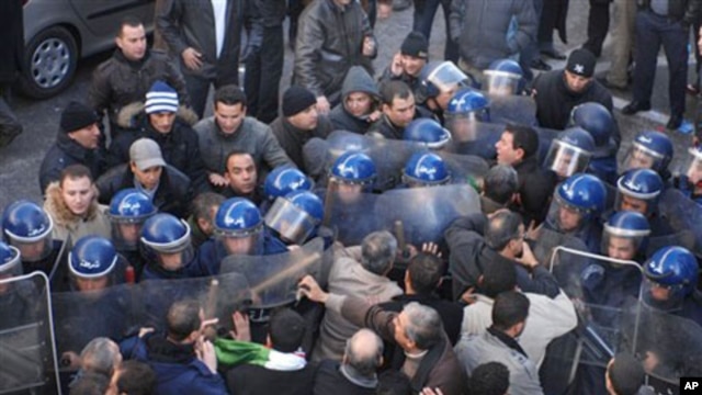 Demonstrators, foreground, asking for political change in  their country, face riot policemen, in Algiers, Algeria, 22 Jan 2011