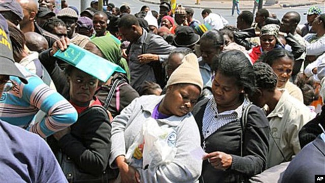A woman seeks shade beneath her ID documents as she joins about 200 Zimbabweans in a queue outside the Home Affairs offices in downtown Johannesburg, 6 Oct 2010.
