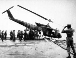 FILE - U.S. Navy personnel aboard the USS Blue Ridge push a helicopter into the sea off the coast of Vietnam in order to make room for more evacuation flights from Saigon, April 29, 1975.