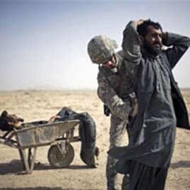 A US Army soldier searches an associate of a suspected Taliban IED placer, seen in a wheelbarrow, who was killed in a coalition missile strike in Zhari district, Kandahar province (File)