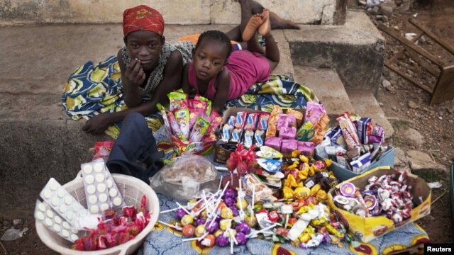  Girls selling sweets watch from their makeshift kiosk - as other boys and girls their age [not pictured] attend school - amid great poverty, in the city of Makeni in Sierra Leone, April 20, 2012.