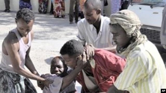 Residents assist a victim who was injured during shelling in Mogadishu's restive Bakara market (File Photo)