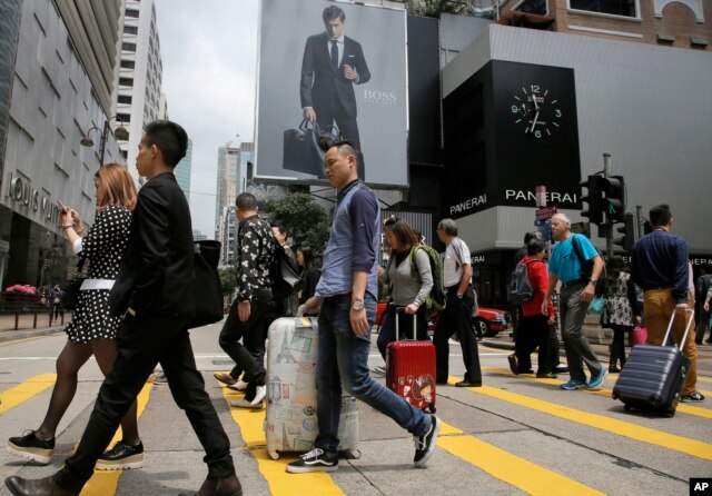 Những du khách Trung Quốc đại lục mang theo vali khi đi bộ tại một khu mua sắm ở Hong Kong, ngày 12 tháng 4 năm 2015.