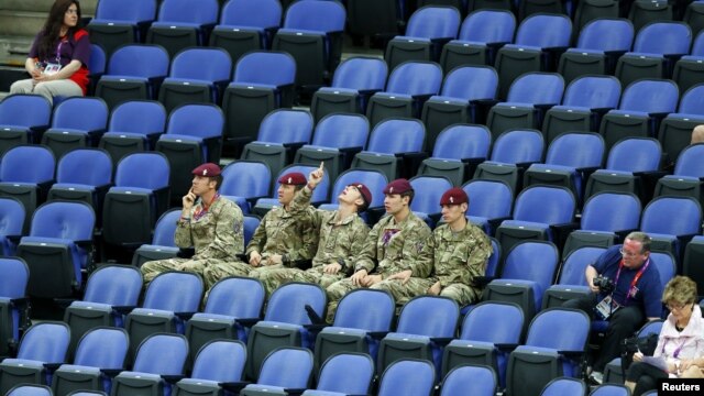 Soldiers sit in the empty seats held by the IOC as they watch the women's gymnastics qualification in the North Greenwich Arena during the London 2012 Olympic Games July 29, 2012.