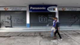 A couple walks past graffiti that reads "Plug The City." The phrase has appeared on various places in the capital, Rangoon, since the government implemented electricity cuts. 