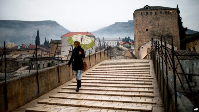 A woman crosses the old bridge in Mostar in Bosnia and Herzegovina, Jan. 20, 2013. The old bridge connects the two sides together and also has a symbolic meaning connecting the two ethnic sides of the city. 