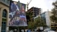 A poster depicting an American negotiator wearing a suit jacket and tie at a negotiating table and a dog to his side is displayed in Palestine square, Tehran, Iran, Oct. 27, 2013.