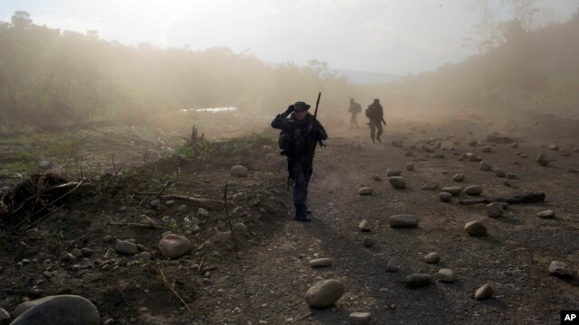 FILE - Counternarcotics officers walk in a clandestine airstrip strewn with boulders, in the Apurimac, Ene and Mantaro River Valleys, or VRAEM, the world's No. 1 coca-growing region, in Junin Peru, Sept. 19, 2014. 