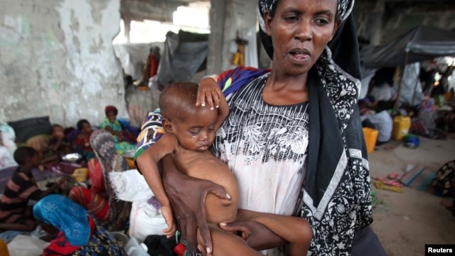 An internally displaced woman holds her malnourished son at a new settlement in Somalia's capital Mogadishu, July 19, 2011. 