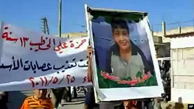 An image grab taken from YouTube on May 28, 2011, shows a Syrian man holding a picture of 13-year-old boy Hamza al-Khatib during his funeral on May 25, 2011 in the flashpoint region of Daraa, Syria