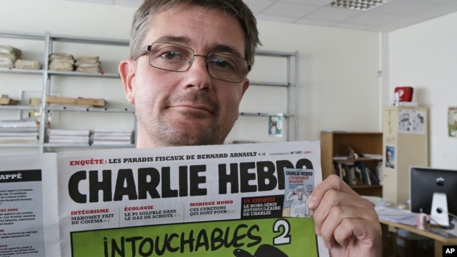 El director de la revista satírica Charlie Hebdo, Charb, muestra la portada de la publicación que presenta caricaturas de Mahoma desnudo.