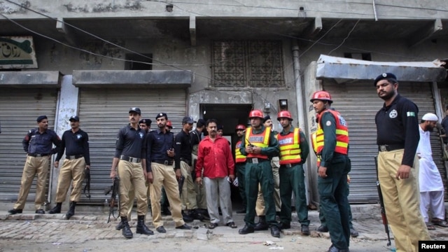 Policemen and rescue workers gather outside a building where unidentified gunmen killed police cadets in Lahore on July 12, 2012. 