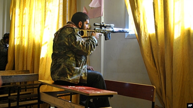 A Syrian rebel aims his rifle inside a classroom at a school in the Deir Baalbeh neighborhood in Homs province, Syria, February 22, 2012.