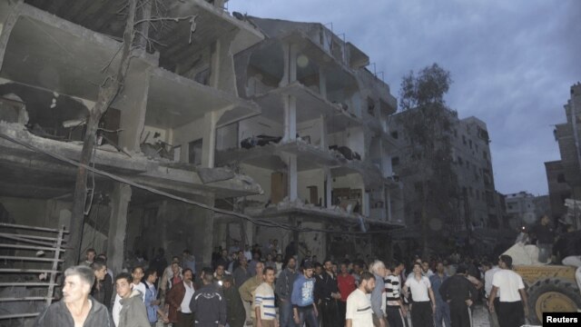 A crowd gathers in front of damaged buildings after a car bomb exploded at Daf al-Shok district, in Damascus, Syria, October 26, 2012, in this photograph released by Syria's national news agency SANA.