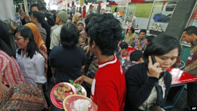 A worker carries a plate of food to be delivered to a customer in Indonesia, Jan. 28, 2011. Indonesia will suspend import duties on rice, soybeans and wheat as part of government efforts to fight inflation as Asian countries grapple with escalating food c