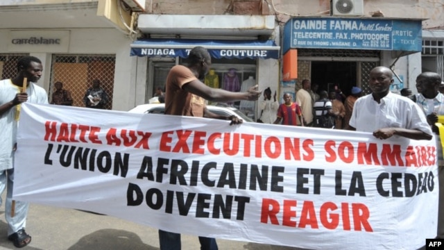Protesters gather outside the Gambian Embassy in Senegal on August 30, 2012. The banner reads: " Stop summary executions. The African Union and ECOWAS must react." 