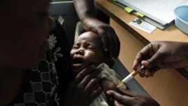 A mother holds her baby as she receives a new malaria vaccine at the Walter Reed Project Research Center in Kenya, October 30, 2009. 