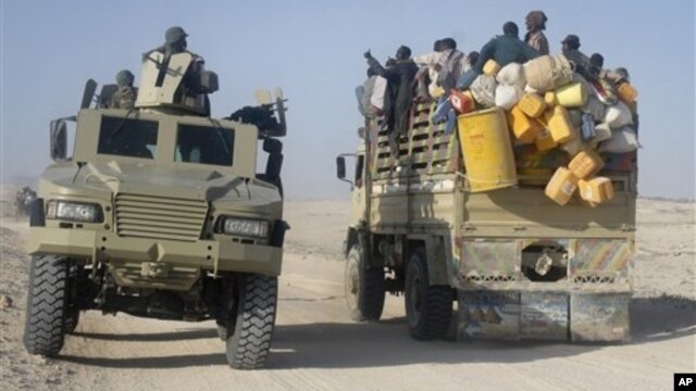East African civilians depart in a truck, right, as AMISOM forces advance on al-Shabab-controlled region, Somalia, Sept. 4, 2012.