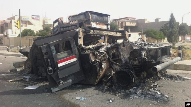 Chiếc xe bọc thép của quân đội Iraq bị đốt cháy trên đường phố của thành phố Mosul, Iraq, ngày 12/06/2014