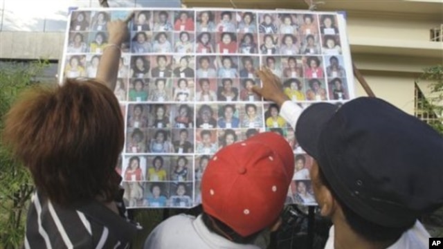 A Cambodian man compares a photo to those of stampede victims at Preah Kossamak Hospital in Phnom Penh, Cambodia, 24 Nov 2010.