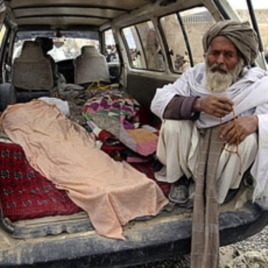 An elderly Afghan man sits in a minivan next to the covered body of a person allegedly shot dead by a U.S. service member in Panjwai, Kandahar province, Afghanistan, March 11, 2012.
