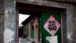 Clothes hang from a green entrance door of a single-story brick house, known as a "black jail" in Beijing, Feb. 5, 2013.