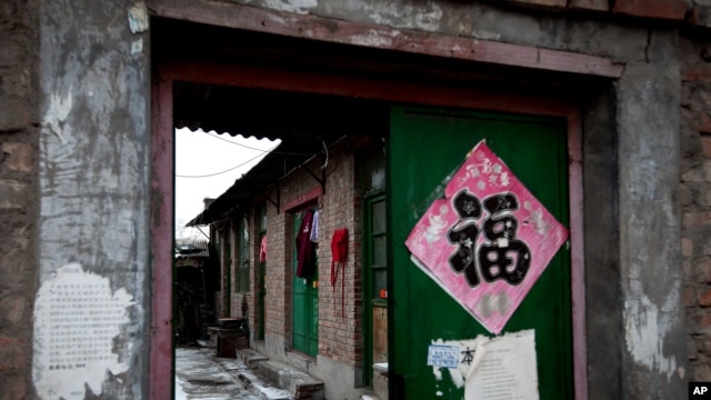 Clothes hang from a green entrance door of a single-story brick house, known as a "black jail" in Beijing, Feb. 5, 2013.