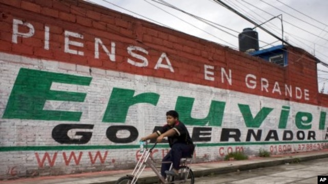 A cyclist rides past a mural for Eruviel Avila, candidate for governor of the state of Mexico for the Institutional Revolutionary Party (PRI) in Toluca, July 2, 2011