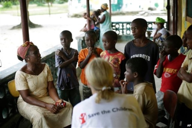 Carolyn Miles (foreground), CEO of Save the Children, listens to orphans at a Liberian government-run facility in Unification town, Oct. 3, 2014.