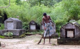 FILE - A worker cleans the ground near the graves at a Jewish cemetery located on the edge of Rangoon, Oct. 2006.