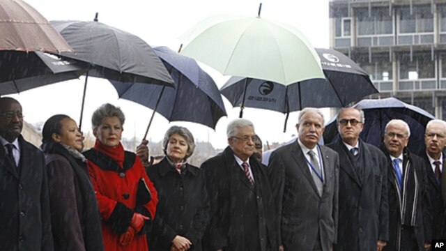 Palestinian President Mahmoud Abbas, center, stands on a podium with UNESCO director general Irina Bokova, fourth from left, and other UNESCO and Palestine government officials in Paris, December 13, 2011.