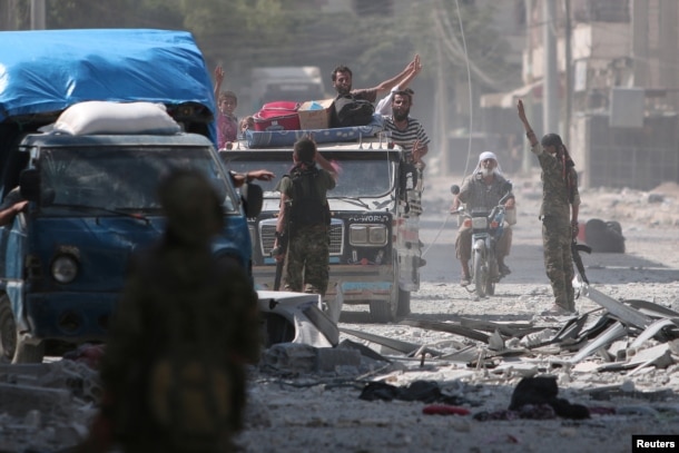 FILE - Syria Democratic Forces (SDF) fighters greet civilians who were evacuated by the SDF from an Islamic State-controlled neighborhood of Manbij, in Aleppo Governorate, Syria, Aug. 12, 2016.