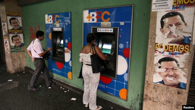 People withdraw money from cash machines where election propaganda supporting Venezuela's President Hugo Chavez cover the nearby walls in Caracas, February 8, 2013. 