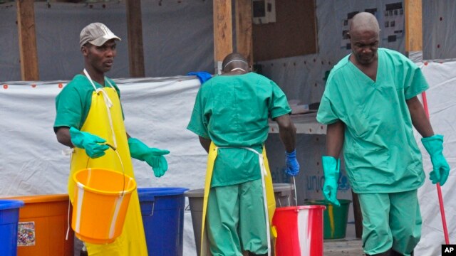 Health workers with buckets, as part of their Ebola virus prevention protective gear, at an Ebola treatment center in the city of Monrovia, Liberia, Aug. 18, 2014. 