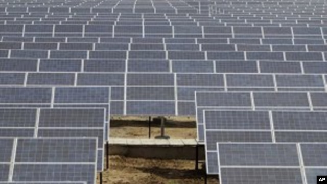 An Indian security guard walks among solar panels at the newly inaugurated solar photovoltaic power plant at Khadoda, in Sabarkantha district, about 90 kilometers (56 miles) from Ahmadabad, India, Friday, June 10, 2011